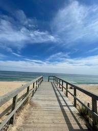 A wooden boardwalk leading to the Atlantic on a bright morning