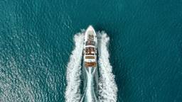 Aerial view of a yacht cutting through teal water