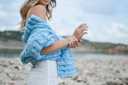 A woman in a soft blue knit on a rocky coastline